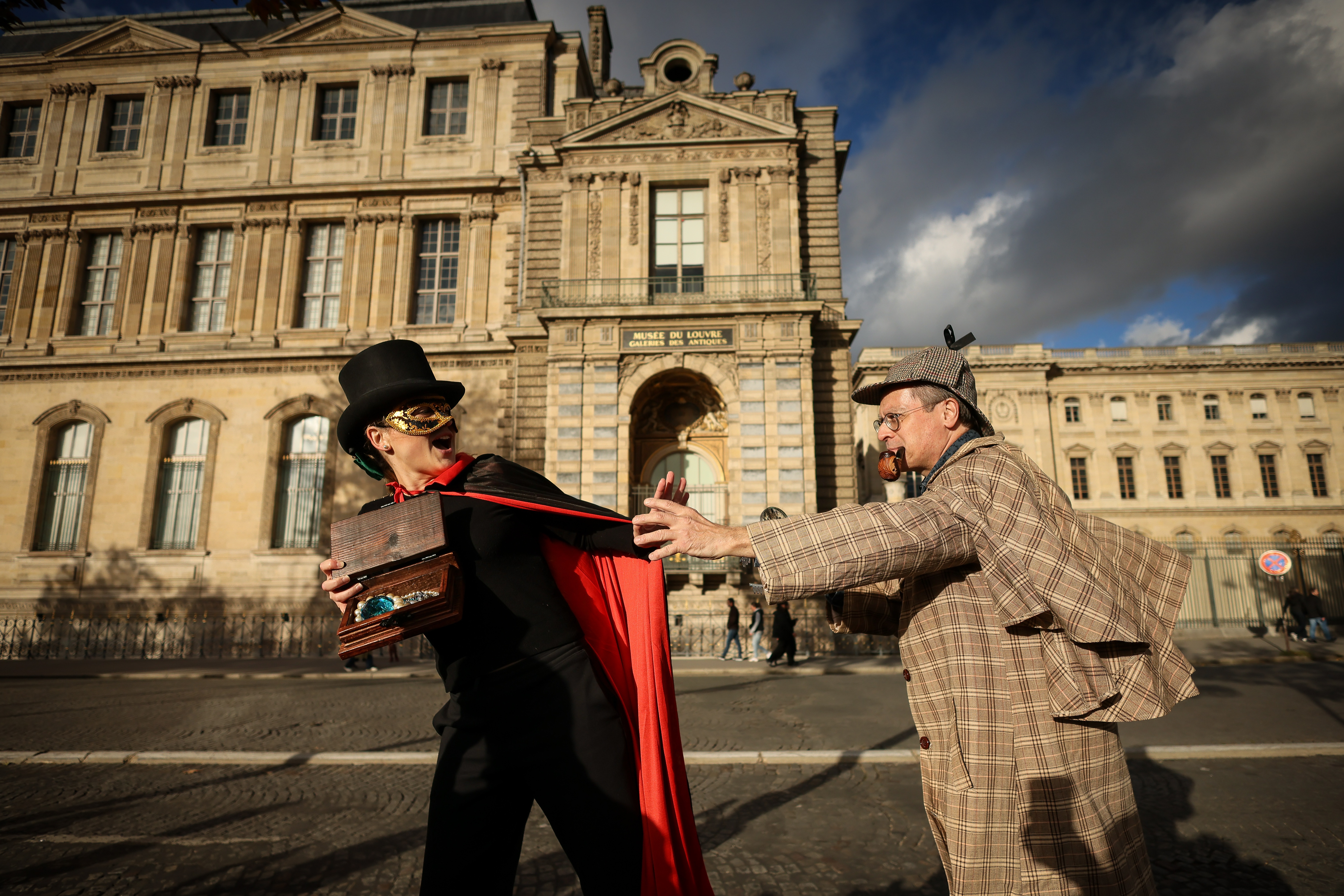 Members of the Paris Holmes Society (Cercle Holmesien de Paris), Laurence Deloision, dressed like Arsène Lupin (left), and Thierry Gilibert, dressed like Sherlock Holmes, on Saturday stage the theft by the facade and the window where thieves entered the Louvre last Sunday.